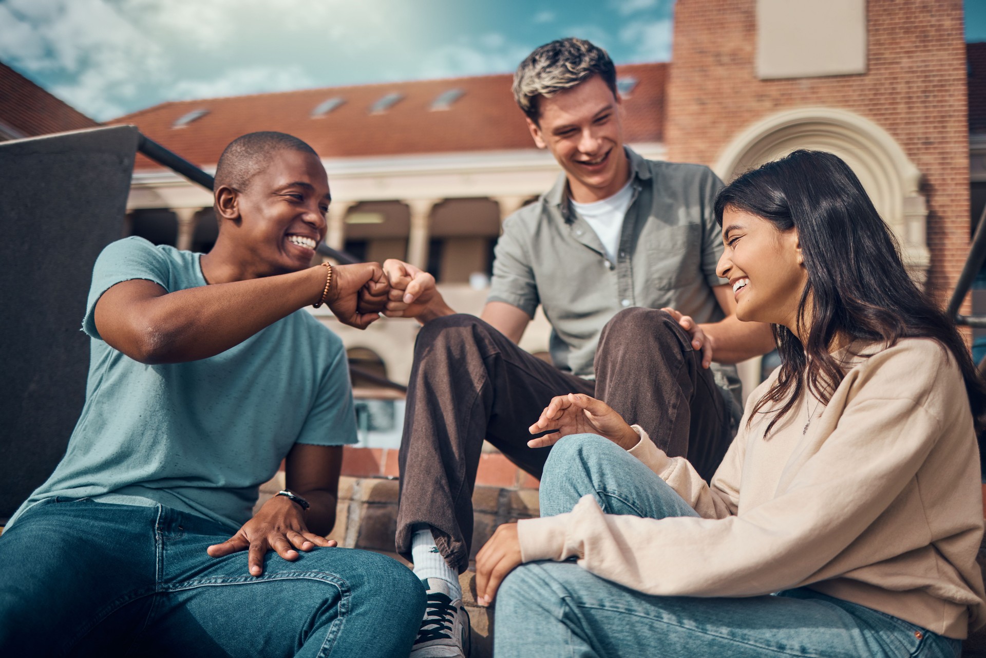 Choque de puños, saludo y estudiantes en la universidad con diversidad, apoyo educativo y trabajo en equipo en la escuela en el campus. Emocionados, metas y amigos hablando sobre becas, estudios y trato en la universidad